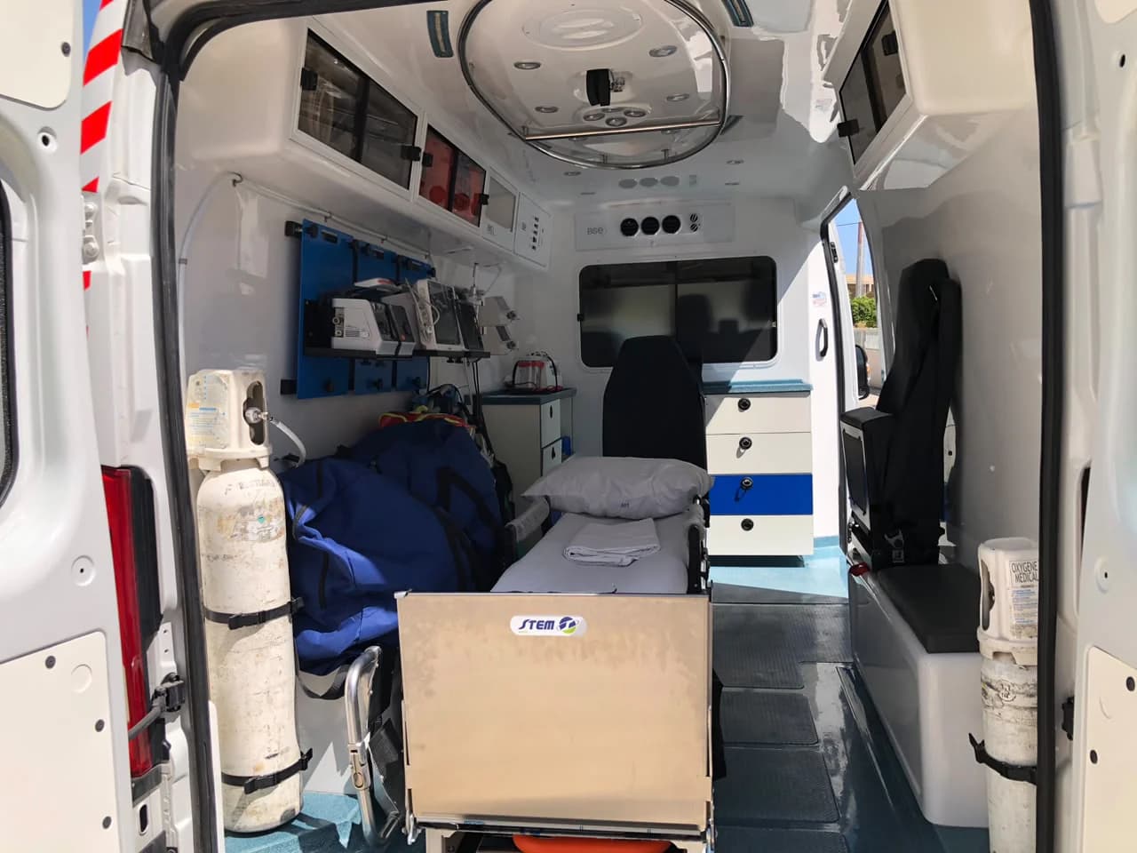 EMS ambulance compartment from the rear: oxygen cylinders, stretcher and seat
