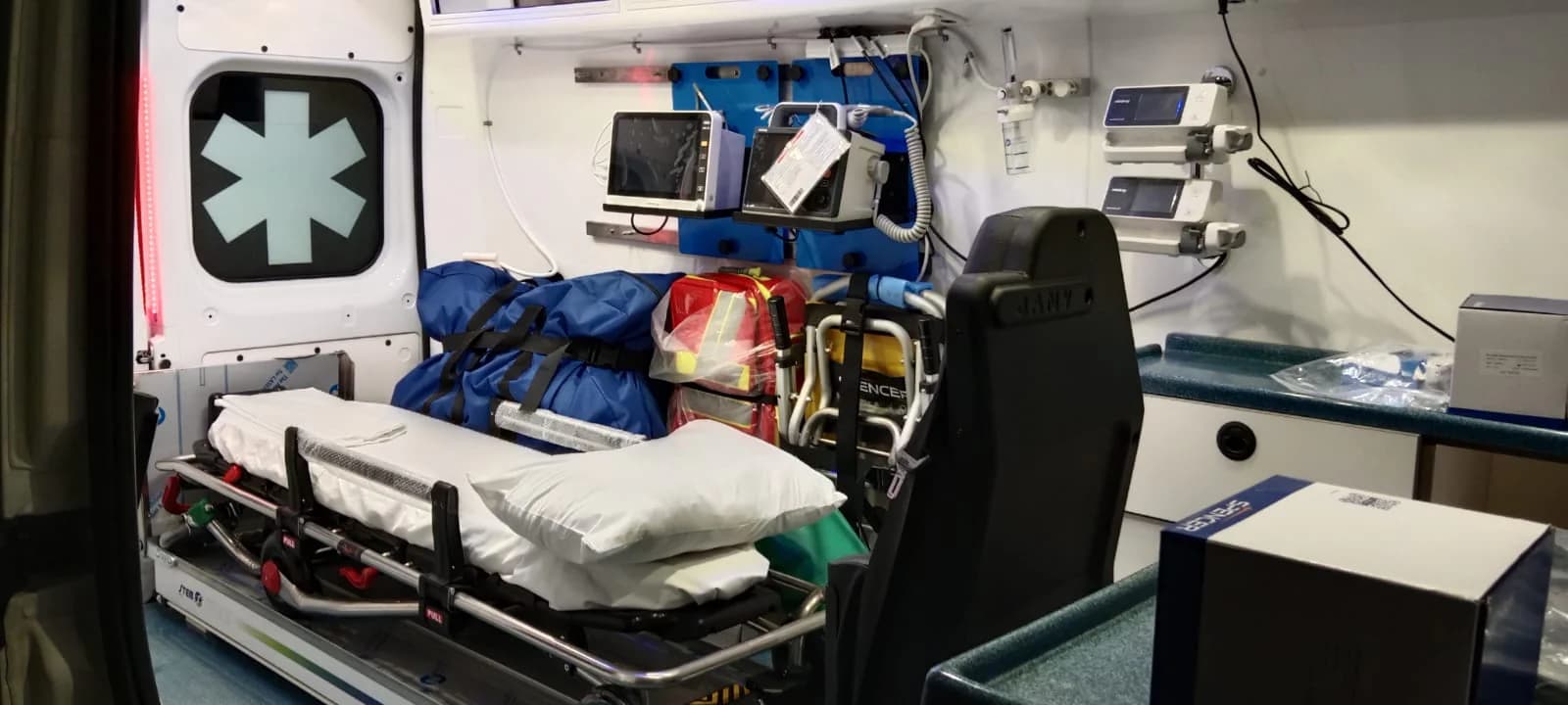 Stretcher, emergency bags and monitors inside an EMS ambulance patient compartment