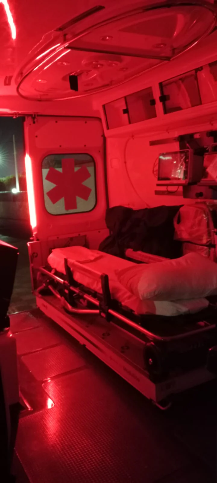 مقصورة سيارة إسعاف EMS تحت إضاءة ليلية حمراء، النقّالة جاهزة